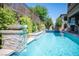 Backyard pool area features a rock waterfall feature, lush landscaping and basketball hoop at 12018 Vento Forte Ave, Las Vegas, NV 89138