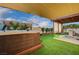 Outdoor patio area with a hot tub, pergola, artificial turf, and a lush green landscape at 167 Thunder Plains Way, Henderson, NV 89012