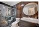 Modern bathroom featuring wood accent wall, marble shower, square sink, and round mirror at 167 Thunder Plains Way, Henderson, NV 89012