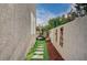 A narrow side yard featuring decorative wall art and artificial turf leading to an outdoor area at 167 Thunder Plains Way, Henderson, NV 89012