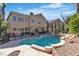 Expansive backyard with a sparkling pool, lush landscaping, and multiple seating areas at 1717 Double Arch Ct, Las Vegas, NV 89128