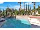 Beautiful in-ground pool surrounded by lush landscaping and palm trees at 1717 Double Arch Ct, Las Vegas, NV 89128