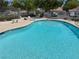 Community pool with crystal clear water surrounded by a sunbathing area with mature trees at 2704 Otter Creek Ct # 101, Las Vegas, NV 89117