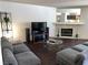 Cozy living room features a stone fireplace, gray sectional, and dark floors at 2704 Otter Creek Ct # 101, Las Vegas, NV 89117