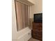 Window with blinds next to a wooden dresser in a neutral-toned room, offering natural light at 4382 Valley Regal Way, North Las Vegas, NV 89032