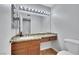 Bathroom vanity features granite counters and wooden cabinets complemented by a large mirror with Hollywood-style lighting at 4680 Freshwater Dr, Las Vegas, NV 89103