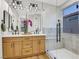 Bright bathroom featuring double vanity, wood cabinets, modern fixtures, and a large glass shower with grey tiling at 4718 Atlantico St, Las Vegas, NV 89135
