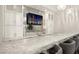 Close-up of an elegant basement bar with marble countertops, backsplash, and custom cabinets at 5 Moonfire Dr, Las Vegas, NV 89135