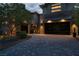 Contemporary home featuring a stone facade, illuminated driveway, and glass garage doors at 5 Moonfire Dr, Las Vegas, NV 89135
