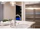 Close-up of a modern kitchen island featuring a white farmhouse sink, marble countertop, and stainless steel refrigerator at 5 Moonfire Dr, Las Vegas, NV 89135
