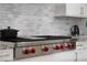 Close-up of a Wolf range with red knobs and marble backsplash in a modern kitchen at 5 Moonfire Dr, Las Vegas, NV 89135