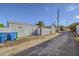 View of the backyard featuring a gray wall, an alley, blue bins, and a partial view of the exterior of the house at 517 7Th St, Boulder City, NV 89005
