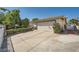 Side view of home with a long driveway, a two-car garage, and mature landscaping at 5181 Morris St, Las Vegas, NV 89122