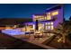 Beautiful backyard view featuring a modern pool, fire pit, lounge chairs, and a contemporary two-story home at night at 5436 Succulent Rose Dr, Las Vegas, NV 89135