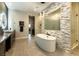 Bright bathroom with freestanding tub, stone accent wall, large shower and dual vanity with modern lighting at 5436 Succulent Rose Dr, Las Vegas, NV 89135