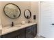 Chic bathroom featuring dual sinks with granite countertops, round mirrors, dark cabinets, and a mosaic shower at 5436 Succulent Rose Dr, Las Vegas, NV 89135