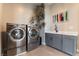 Functional laundry room features a modern washer and dryer, cabinetry, a sink, and stylish decor at 5436 Succulent Rose Dr, Las Vegas, NV 89135