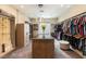 Well-organized walk-in closet features custom shelving, racks, a central island, and a cozy ottoman at 5436 Succulent Rose Dr, Las Vegas, NV 89135