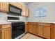Well-lit kitchen features wood cabinets, black appliances, and tile flooring at 5655 E Sahara Ave # 2044, Las Vegas, NV 89142