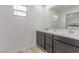 Bathroom features double sinks with modern cabinetry, a large mirror, and wood look floors at 6150 Foxes Dale St, Las Vegas, NV 89166