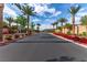 Community street view with a palm tree lined road and blooming flower beds at 6150 Foxes Dale St, Las Vegas, NV 89166