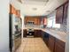 The kitchen features stainless steel appliances, including a refrigerator and oven, along with wooden cabinets and tile floors at 6215 Don Zarembo Ave, Las Vegas, NV 89108