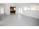 Bright living room with a view to the kitchen with wooden cabinets, a glass patio door, large windows, and light colored flooring at 6215 Don Zarembo Ave, Las Vegas, NV 89108