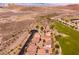 An aerial view shows residential homes bordered by a green golf course and desert terrain at 63 Via Di Mello, Henderson, NV 89011