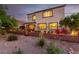 Cozy backyard patio with brick walls, seating, and blooming flowers at dusk at 63 Via Di Mello, Henderson, NV 89011