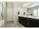 Bathroom featuring double sinks, dark cabinets, tile flooring, and a glass shower door at 63 Via Di Mello, Henderson, NV 89011