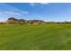 A scenic view of a lush green golf course with desert mountains in the background on a sunny day at 63 Via Di Mello, Henderson, NV 89011