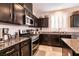 Close-up of kitchen features dark cabinets, granite countertops, and stainless steel oven at 63 Via Di Mello, Henderson, NV 89011