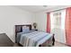 Simple bedroom with a wood-framed bed, striped bedding, and a window with patterned curtains for a relaxing atmosphere at 8059 Wards Ferry St, Las Vegas, NV 89139