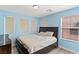 Bright bedroom with light blue walls, wood-look floors, and a bed with white bedding and multiple windows at 8059 Wards Ferry St, Las Vegas, NV 89139