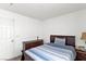 Minimalist bedroom with a dark wood bed frame and dresser, complemented by neutral bedding and white walls at 8059 Wards Ferry St, Las Vegas, NV 89139