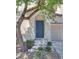 Close-up of a home's front door framed by a mature tree and manicured landscaping at 8824 Charm Canyon Ave, Las Vegas, NV 89178