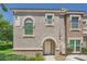 Two-story townhome featuring stucco exterior, arched entryway, and well-maintained landscaping at 10001 Peace Way # 2335, Las Vegas, NV 89147