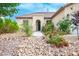 Welcoming front entrance with desert landscaping, featuring rocks, shrubbery, and a charming tiled roof at 1027 Dawn Valley Dr, North Las Vegas, NV 89031