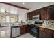 Open kitchen with dark wood cabinetry, granite countertops, and stainless steel appliances, seamlessly connected to the living area at 1027 Dawn Valley Dr, North Las Vegas, NV 89031