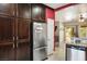 Well-appointed kitchen with dark wood cabinets, stainless steel refrigerator, and an open view to the living room at 1027 Dawn Valley Dr, North Las Vegas, NV 89031