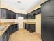View of the kitchen showcases dark cabinetry, stone countertops, tile flooring, and stainless steel sink at 1030 Maple Pines Ave, North Las Vegas, NV 89081