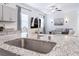 Kitchen island showcasing a stainless steel sink and granite countertops, and an open view to the living area at 10943 Artisan Ranch Ave, Las Vegas, NV 89166