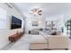 Open-concept living room with a ceiling fan, large sectional sofa, and mounted TV with modern decor at 10943 Artisan Ranch Ave, Las Vegas, NV 89166