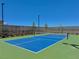 Well maintained community tennis court surrounded by a dark fence with a clear blue sky overhead at 10943 Artisan Ranch Ave, Las Vegas, NV 89166