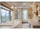 Bright bathroom featuring a soaking tub with an oversized window and marble countertops at 1413 Iron Hills Ln, Las Vegas, NV 89134