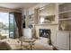 Cozy living room featuring a fireplace, built-in shelving, and a seamless transition to the outdoor balcony at 1413 Iron Hills Ln, Las Vegas, NV 89134