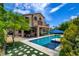 Backyard featuring a modern pool, covered patio area, lush landscaping and inviting lounge spaces at 1701 Tesara Vista Pl, Las Vegas, NV 89128