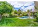 Expansive backyard with lush green lawn, mature trees, and a sparkling pool at 1701 Tesara Vista Pl, Las Vegas, NV 89128