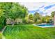 Lush backyard featuring a well-manicured lawn, beautiful trees, and a refreshing swimming pool at 1701 Tesara Vista Pl, Las Vegas, NV 89128