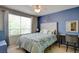 Comfortable bedroom with blue accent wall, queen bed, ceiling fan, and a large window at 1701 Tesara Vista Pl, Las Vegas, NV 89128